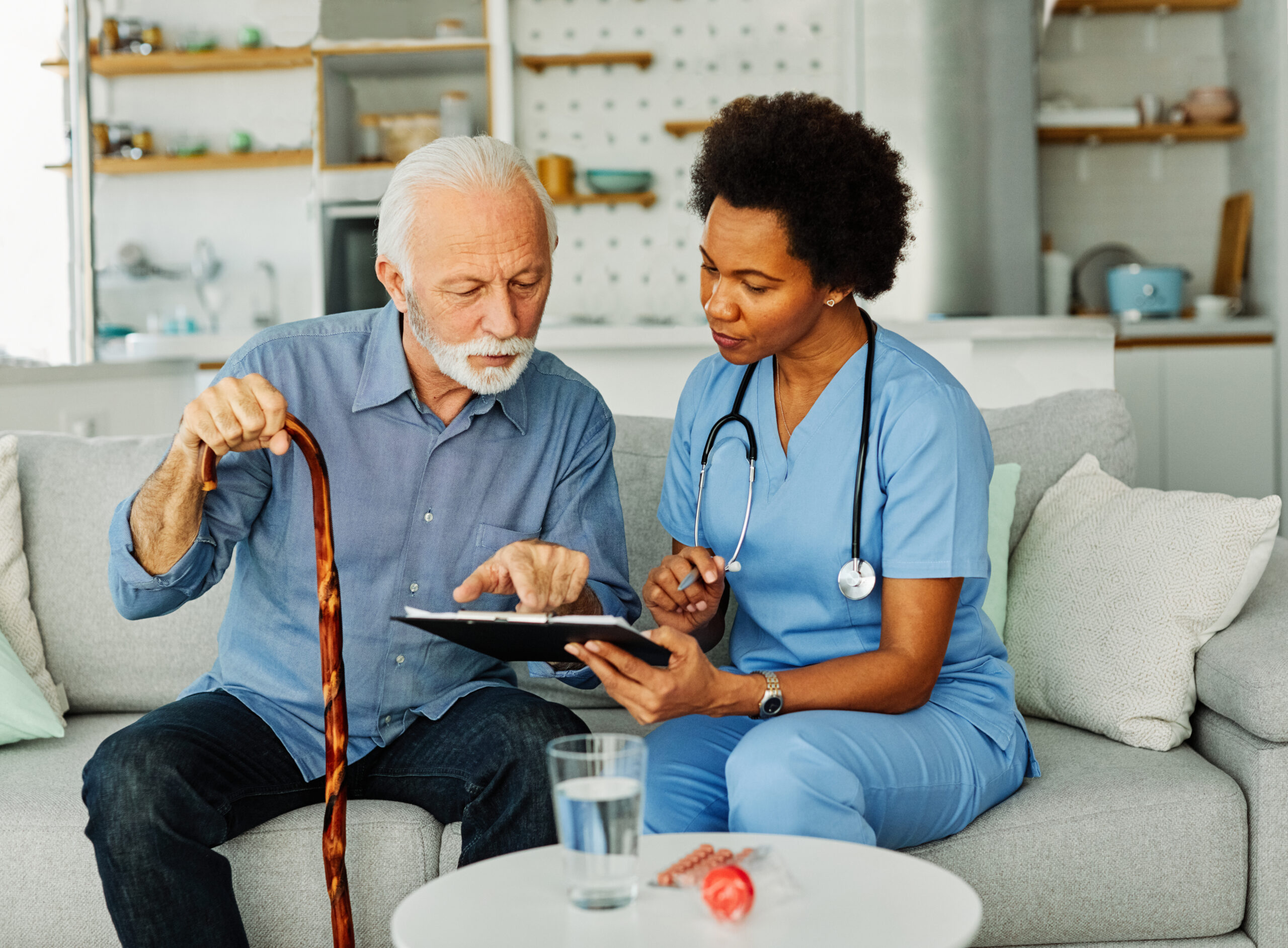 Doctor or nurse caregiver with senior man holding walking cane at home or nursing home