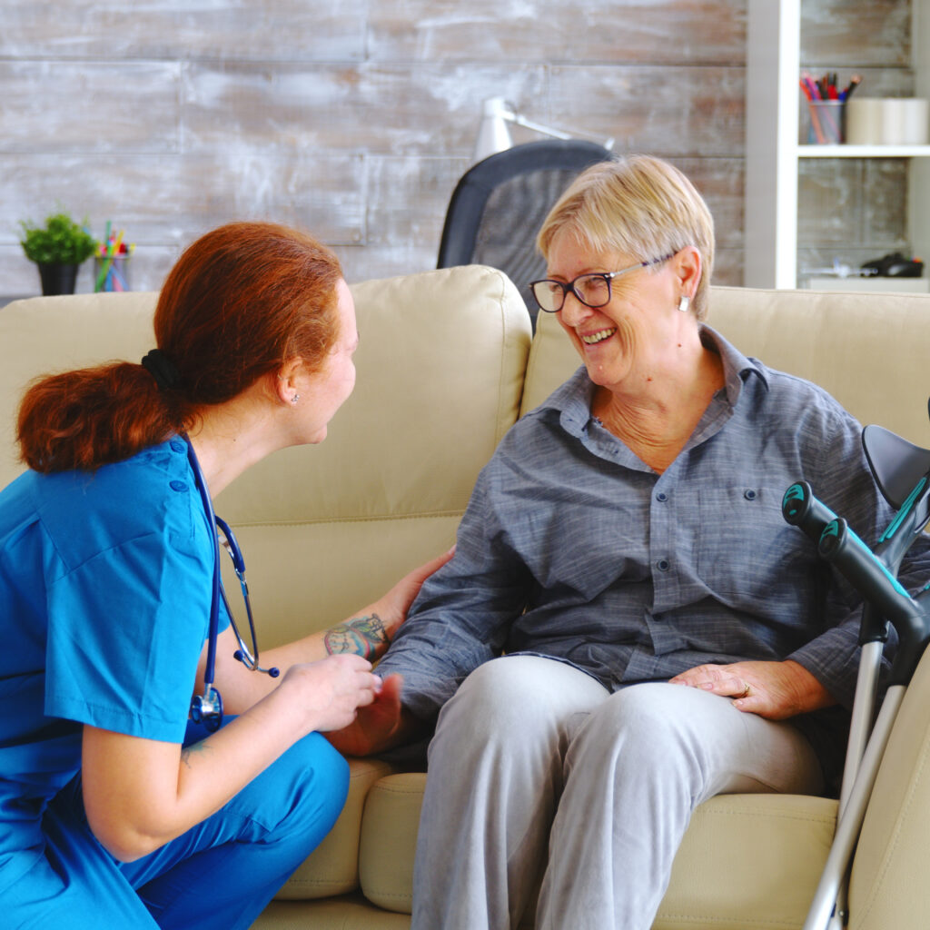 Female nurse talking with old woman with alzheimer in nursing home